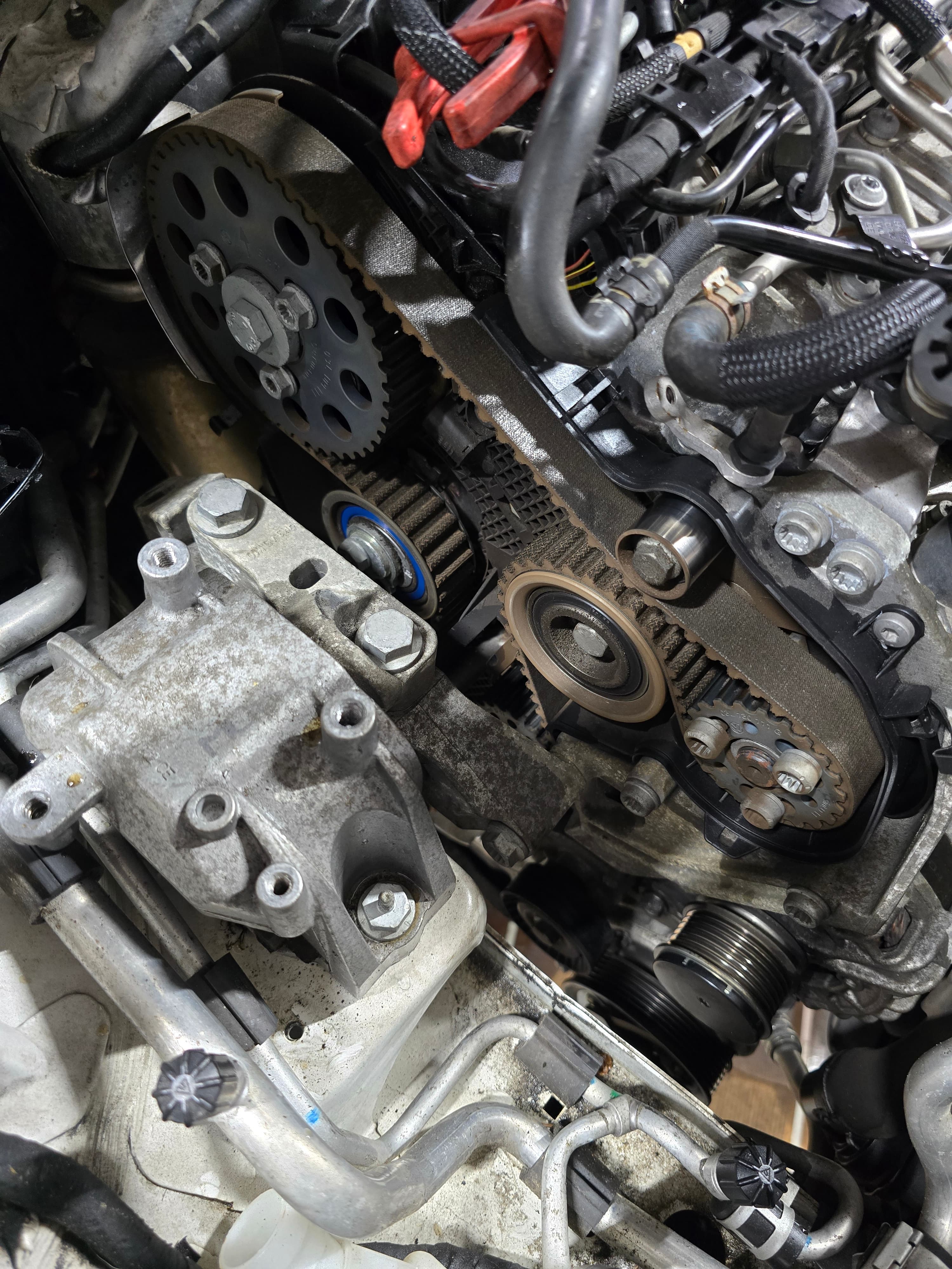 Exposed timing belt, pulleys, and engine mount inside a car's engine compartment.