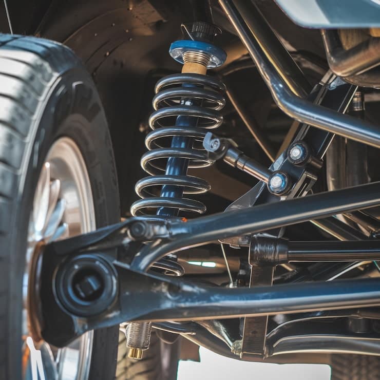 Close-up of a vehicle's suspension system featuring a black coil spring and blue shock absorber.